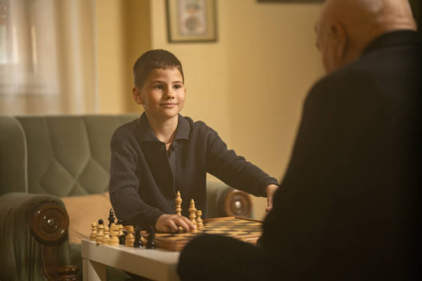 Boy playing chess with grandfather stock photo