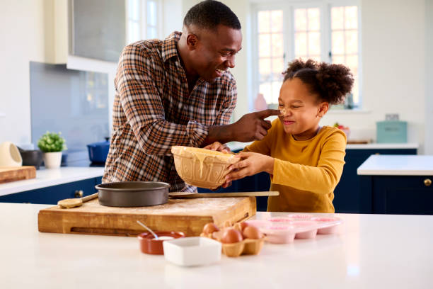 Family Shot With Father And Daughter Having Messy Fun Baking At Home In Kitchen stock photo
