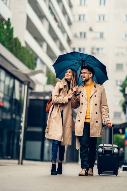 istock beautiful smiling young couple walking in the rain 1459360190