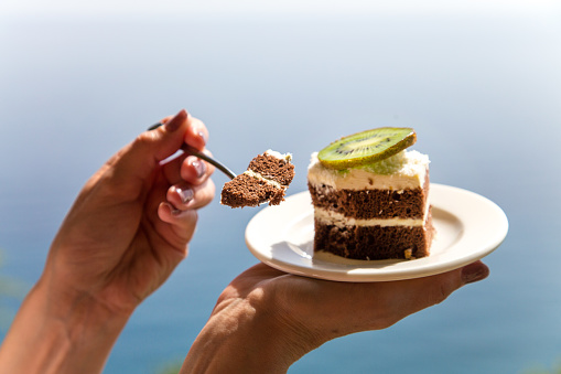 Beautiful chocolate cake with a slice of kiwi white plate against the backdrop of the sea.
