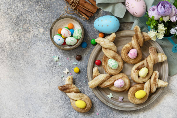 istock Easter rabbit-shaped buns puff pastry with  cinnamon on a stone tabletop. Easter bake idea. View from above. Copy space. 1459360347