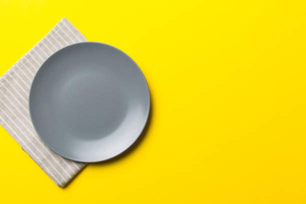 istock Top view on colored background empty round gray plate on tablecloth for food. Empty dish on napkin with space for your design 1459360696