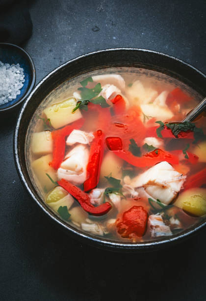 istock Fish soup with cod, paprika, potatoes, tomatoes and parsley in ceramic soup bowl on dark table background, top view 1459361613