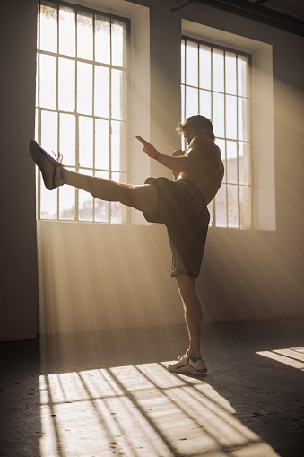 Photo of a strong kickboxer working out at an empty industrial district in golden hour