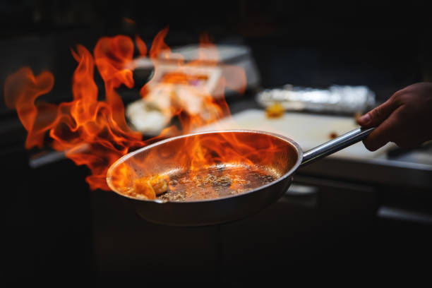Chef main dans la cuisine du restaurant avec poêle, cuisson flambée sur les crevettes - Photo
