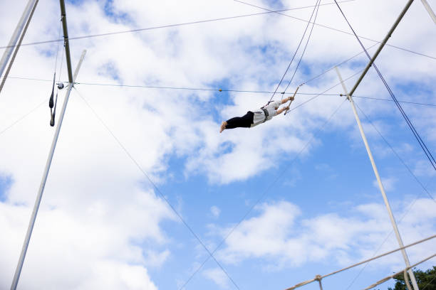 istock Mature trapeze artist flying in the blue sky 1459363621