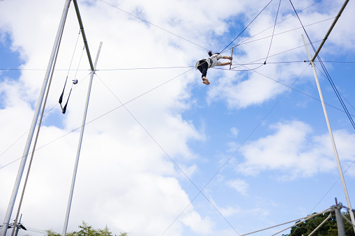 Mature trapeze artist flying in the blue sky