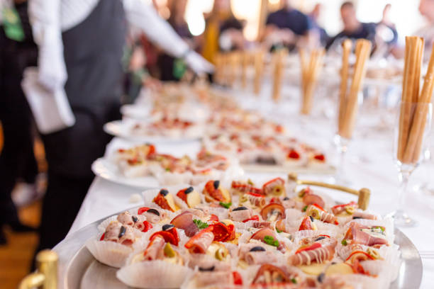 Various canapes appetizers served on buffet table. Waiter in the background. Canapes appetizer close up. Restaurant celebration concept. food service occupation food and drink industry party buffet stock pictures, royalty-free photos & images