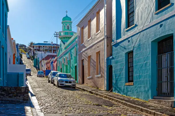 Old cobbled street with mosque and brightly coloured houses in the Bo-Kaap area of the Cape Town CBD, South Africa