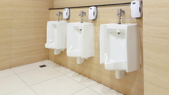Row of urinals men public toilet. Close up white urinals in men's bathroom.