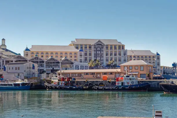 Hotel and shopping centre at Cape Town Waterfront next to jetty and small tugboats