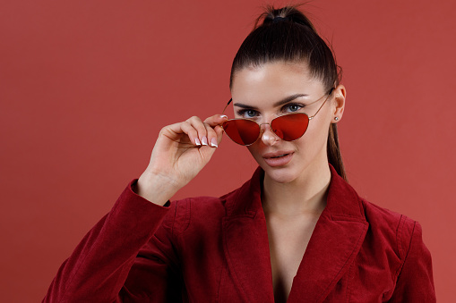 Young smiling caucasian 30s woman in red sunglasses and velvet jacket face portrait.