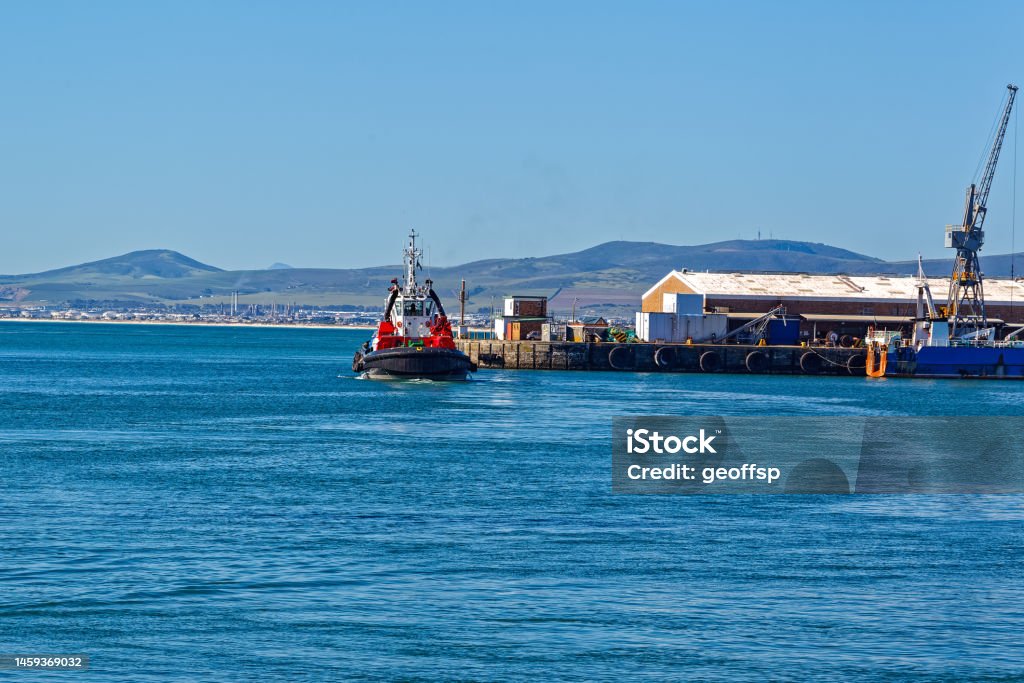 Tug boat entering Cape Town harbour Powerful tug boat entering Cape Town harbour with Milnerton refinery in background Bay of Water Stock Photo