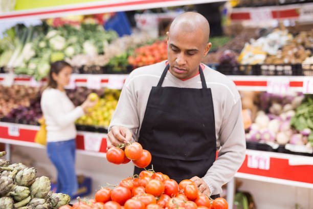 istock Spanish employee in  vegetable store with red ripe tomatoes 1459369237