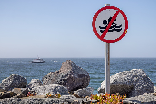 Warning sign to swimmers with inflatable rescue boat in the background