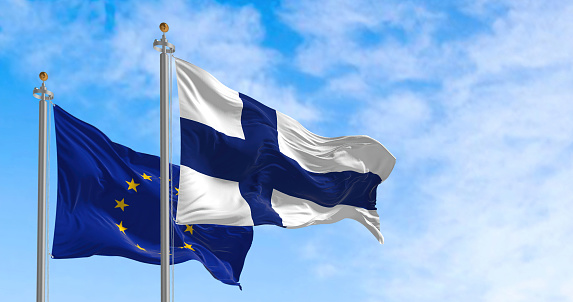 The flags of Finland and the European Union waving together on a clear day. Finland became a member of the European Union on 1995. Realistic 3d illustration. International treaty and diplomacy