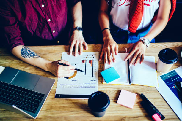 istock Faceless guy pointing at chart of project working with partner 1459374177