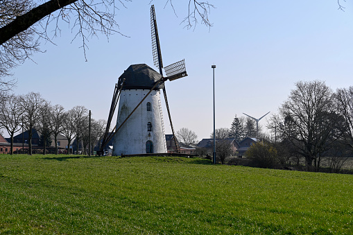 Nettetal, March 5, 2022 - The historic Stammen mill is a listed tower windmill with codend in Hinsbeck / Nettetal - in the background a modern wind turbine / wind power plant.