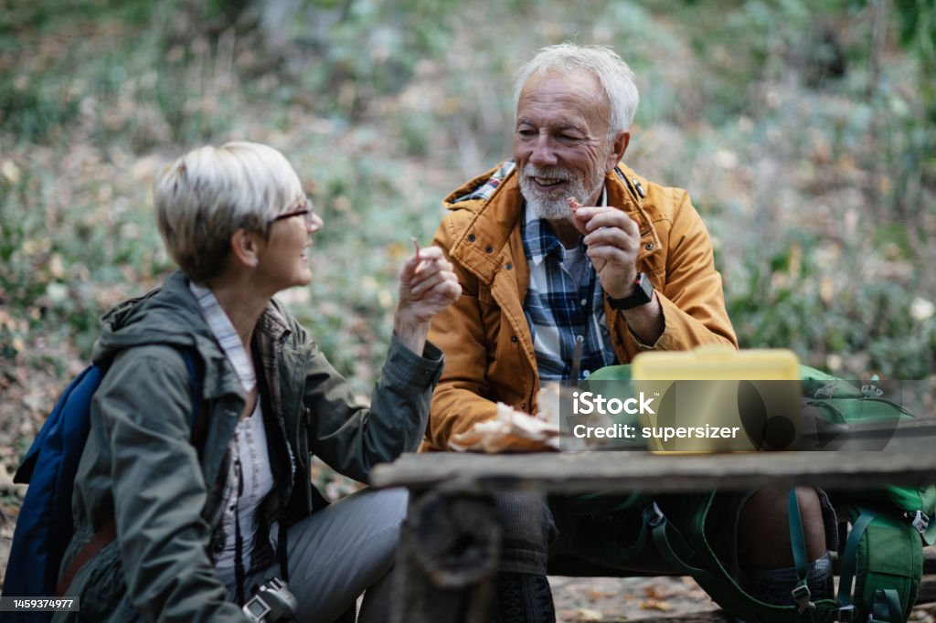My fav food Senior couple sitting on the forest bench and taking a break from hiking. They are eating food that gives them strength 55-59 Years Stock Photo