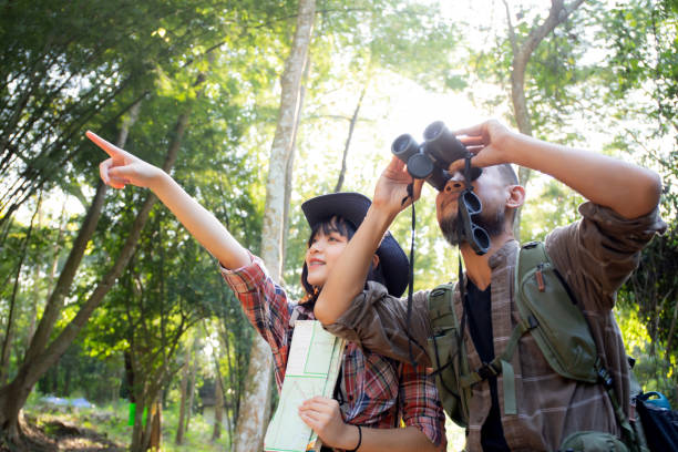 Family with father and daughter tourist backpack hiking doing activity while father looking binoculars in holiday together, man and teenager woman journey adventure trip and looking map. stock photo