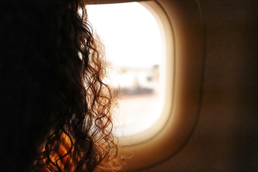 pretty woman looking at the landscape through the window of the plane