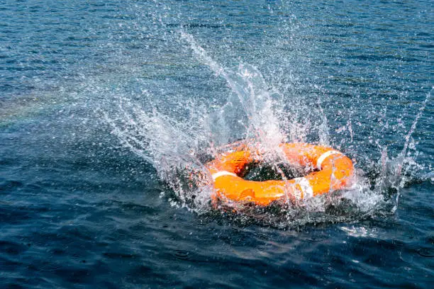 Orange lifebuoy in the sea on the water. The lifebuoy fell with a splash to the surface of the water, motion blur