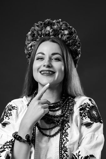 B/W Portrait of ukrainian woman in traditional ethnic clothing and floral red wreath on studio background. Ukrainian national embroidered dress call vyshyvanka. Pray for Ukraine