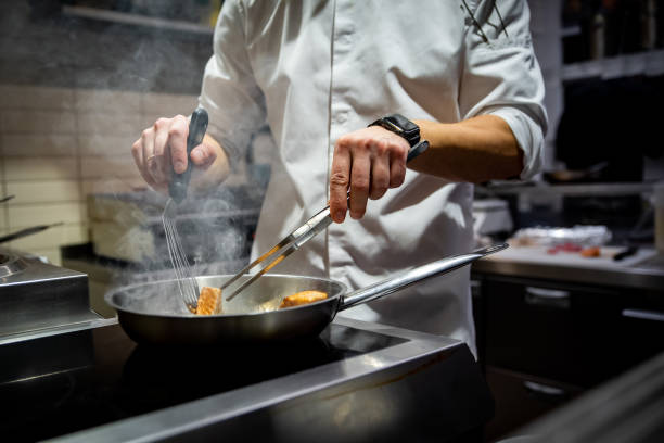 istock man chef cooking fried salmon fish in frying pan on kitchen 1459380640