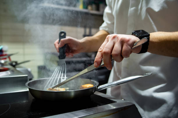 istock man chef cooking fried salmon fish in frying pan on kitchen 1459380644
