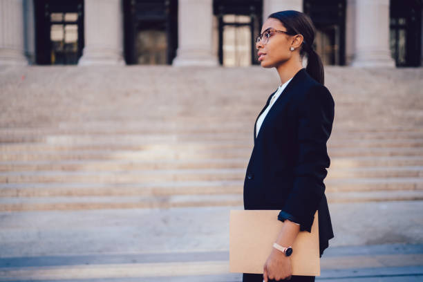 istock Serious black woman with folder walking along monumental building 1459381951