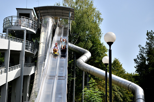 Smiling teenage girl sliding down on toboggan in the summer at an amusement park