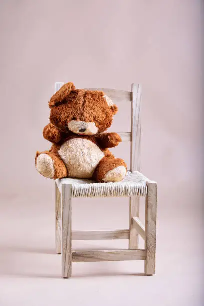 old teddybear on wooden chair