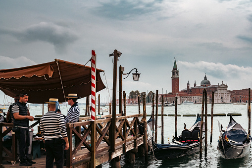 Venice, Italy: October 24, 2022 Gondoliers and Gondolas with San Giorgio Maggiore at sunset,  San Marco, Venice, Italy