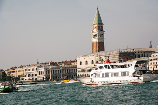 Venice, Italy: October 24, 2022 Boat ferry for transporting passengers and tourists in Venice and Saint Mark Bell tower