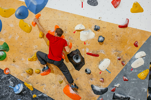 Handsome young athletic man climbing on an indoor climbing wall.