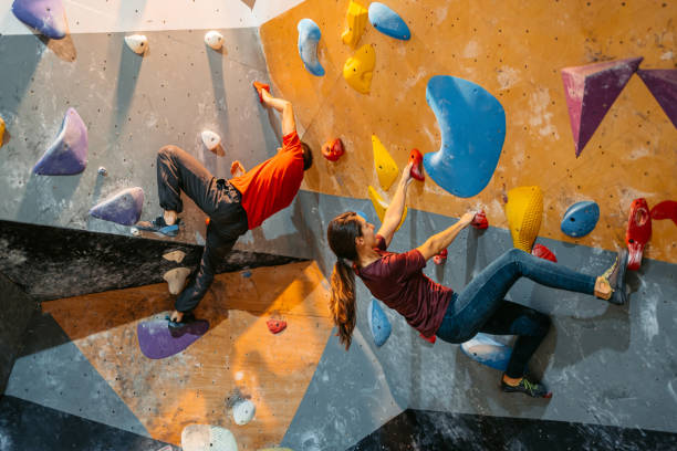 istock Young Man And Woman Climbing On A Climbing Wall 1459388238