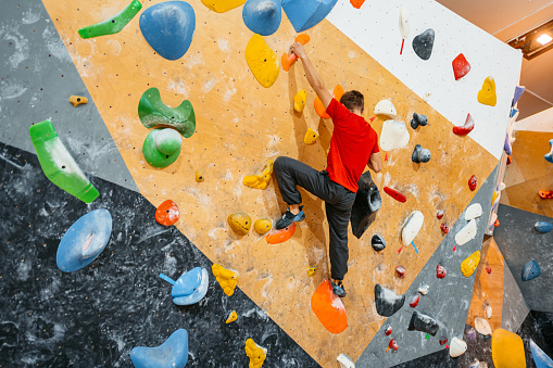 Handsome young athletic man climbing on an indoor climbing wall.