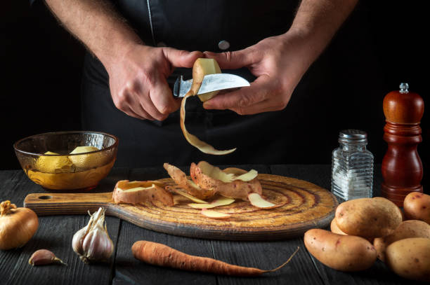 istock The chef peels raw potatoes in a restaurant kitchen before preparing a national dish. Close-up of a cook hands with a knife while working 1459389981