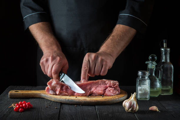 istock The cook cuts meat with a knife before baking. Spices on the kitchen table in a restaurant for preparing a delicious lunch. 1459389982