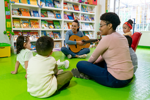 istock Children singing songs in music class and teacher playing the guitar 1459390075