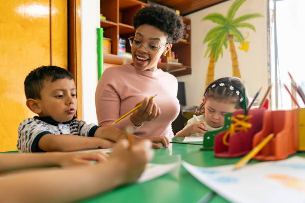 istock Arts teacher supervising little students coloring in class 1459390096