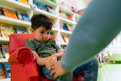 Sad Latin American boy being touched in the leg at school - child abuse concepts