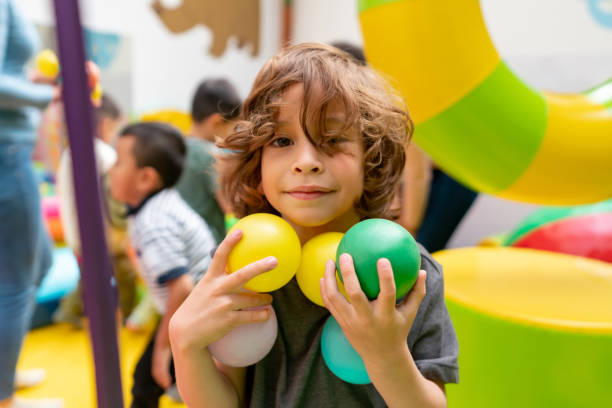 Portrait of a happy Latin American boy playing with balls at the playground and looking at the camera