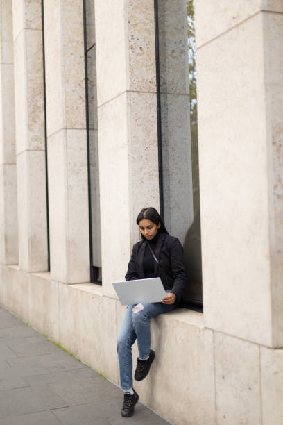 istock Young student woman sitting outside with laptop 1459390508