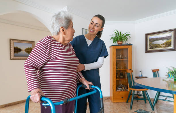 aide à domicile aidant une femme âgée à utiliser un déambulateur à la maison - home caregiver senior adult community outreach nursing home photos et images de collection