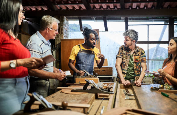 istock Carpenter explaining the use of metal planner to students standing in a woodwork class 1459392544