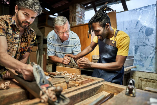 Carpenter helping senior student in woodwork class