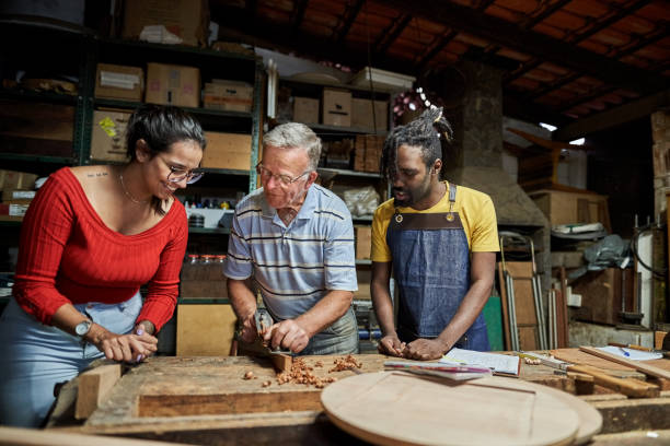 istock Two people learning to use wood planer with mentor in woodwork class 1459392626