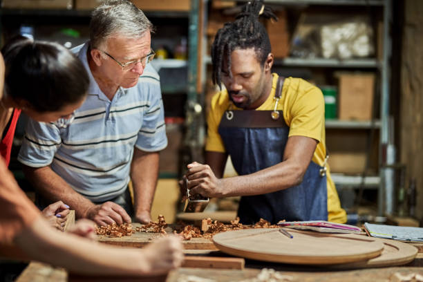 istock Carpenter showing how to plane the wood using a planer at woodwork class 1459392627