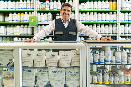 Latin American retail clerk working at a shop selling fertilizers and looking at the camera smiling